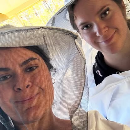 Beekeepers in veils smiling at the hives